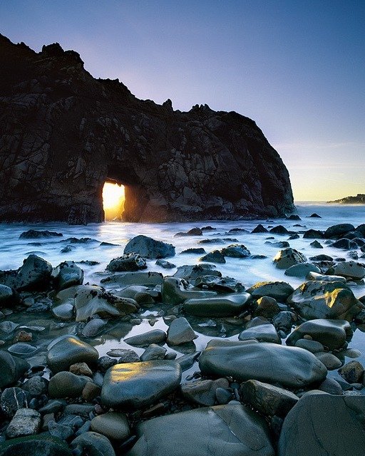 Sunlight Filtering Through Mountain Along A Beach